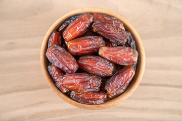 Date fruit in bowl on wooden background, top view