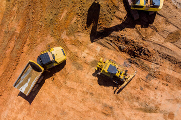 Digger on earthworks in excavator dig the trenche at construction site on arial view of earth...