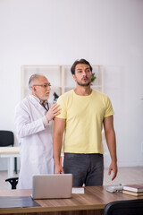 Obraz premium Young male patient visiting old male doctor