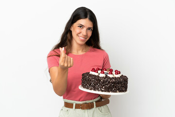 Young caucasian woman holding birthday cake isolated on white background making money gesture