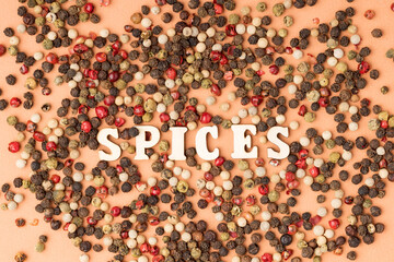spices written from wooden letters between peppercorns