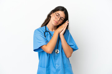 Young surgeon doctor caucasian woman isolated on white background making sleep gesture in dorable expression