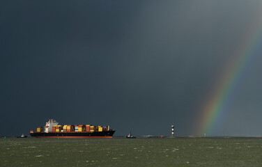 Netherlands, Rotterdam, Rainbow over container ship entering port