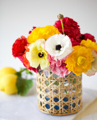 Wicker Vase with Red, Orange, White, Yellow Ranunculus Flowers