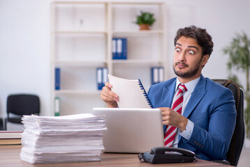 Obraz premium Young male employee and too much work in the office