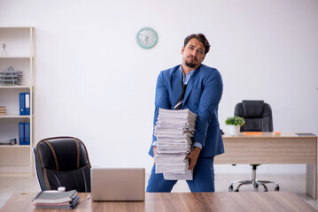 Young male employee unhappy with excessive work in the office