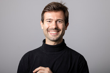 Retrato de estudio de hombre joven sonriendo vestido con suéter negro