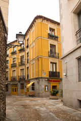 Alley in the center of Madrid, Spain. One totally yellow stands out among the buildings. 