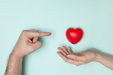 Fototapeta premium Woman hands holding red heartand man hand pointing to the heart, health care, donate and family insurance concept, world heart day, world health day, CSR responsibility, adoption foster family.