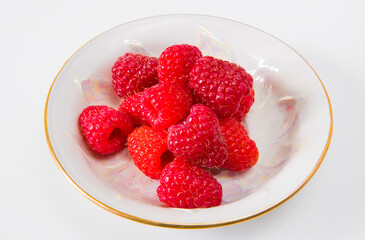 Raspberries on a plate on a white background.