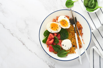 Breakfast. Potatoes latkes with sour cream, spinach salad, tomatoes and boiled eggs on light marble table background.  Delicious food for breakfast. Top view.