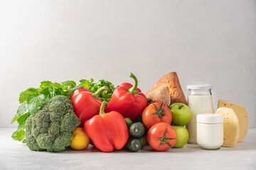 Grocery set of broccoli, lettuce, sweet red pepper, tomatoes, cucumbers, apples, lemon, milk, bread, cheese. The concept of healthy, organic, fresh food, grocery delivery
