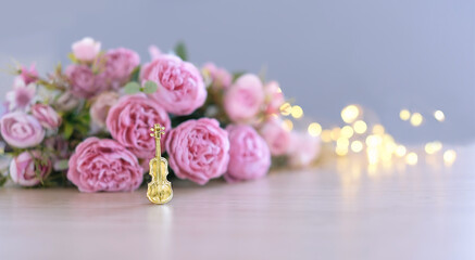 decorative miniature golden violin and rose flowers close up on blurred abstract background. Spring Summer music concept. beautiful romantic composition. copy space