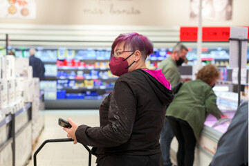 Woman wearing face mask buying in supermarket.