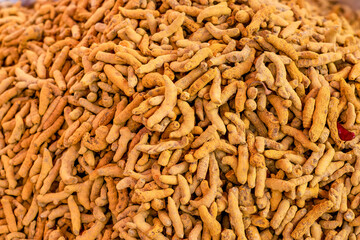 A pile of dried yellow turmeric roots close up top view