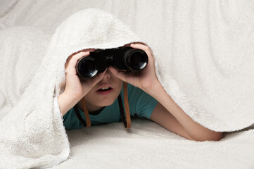 a young detective watches from an ambush using binoculars