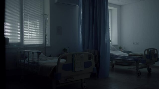 Dark empty hospital room interior with abandoned neat beds shuttered windows.