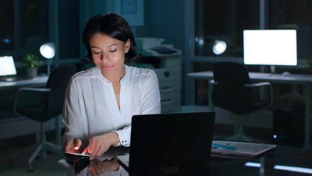 Portrait of businesswoman receiving displeasing email on cellphone working late in office 