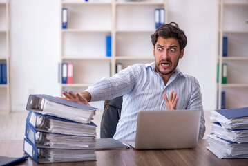 Young male employee unhappy with excessive work in the office