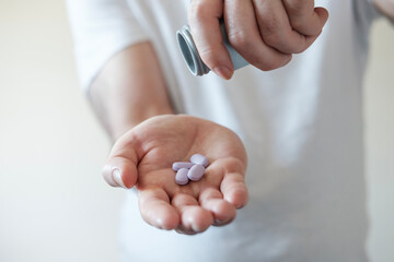 Right man hand holding four pills under pill bottle.
