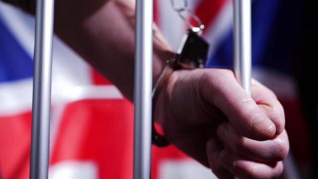 Prisoner in handcuffs through prison bars