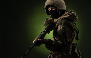 a Russian soldier in a helmet in military clothes with a Kalashnikov assault rifle on a dark...