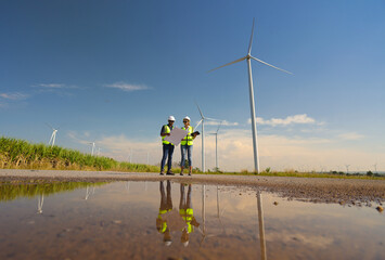 Male an Female colleague read drawing work at out door of Wind turbine farm, Green energy and...