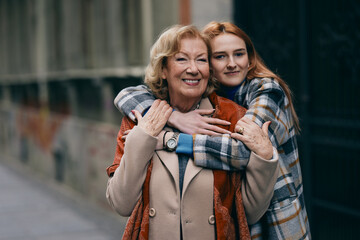 A happy grandmother and granddaughter hugs outside. - 495518345