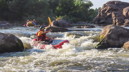 A man rowing inflatable packraft on whitewater of mountain river. Concept: summer extreme water sport, active rest, extreme rafting.