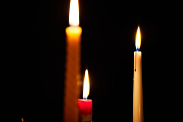 Three candles burn in the dark. The concept of waiting for a holiday and comfort in winter. Front view.