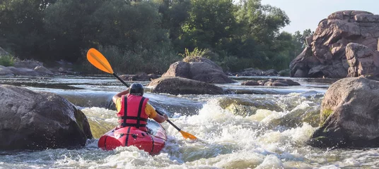  A man rowing inflatable packraft on whitewater of mountain river. Concept: summer extreme water sport, active rest, extreme rafting. © Oleksandra