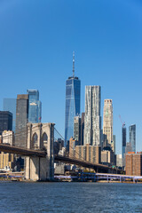 Lower Manhattan skyscraper stands behind Brooklyn Bridge beyond the East River on November 5, 2021 in New York City NY USA. NYC Ferry runs on East River.