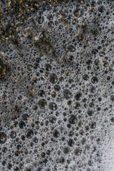top view of a foamy sea wave breaking on a summer pebble beach