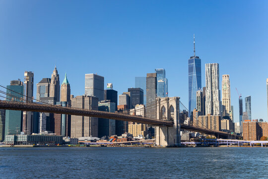 Lower Manhattan skyscraper stands behind Brooklyn Bridge beyond the East River on November 5, 2021 in New York City NY USA. NYC Ferry runs on East River.