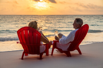 Senior couple relaxing by ocean at sunset Bahamas