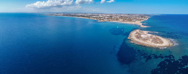 Aerial drone view of island and beach of Isola delle Correnti. Lighthouse surrounded by clear turquoise sea water in Portopalo di capo Passero, Sicily