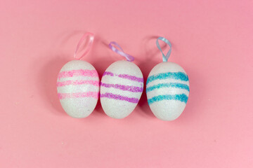 Three Easter eggs of different colors on a pink background. Abstract Easter background. A copy of the space