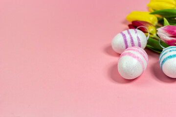 Easter border composition with Easter eggs and yellow and red tulips on a pink background. A stylish concept of minimalist decor. Space for copying. Festive flat banner with greeting card