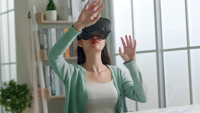 Young Asian woman feeling excited while using 360 VR headset for virtual reality, metaverse at home