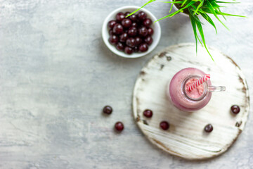 A bottle of cherry smoothies on a white background, cherries in bulk and in a plate. Morning summer breakfast