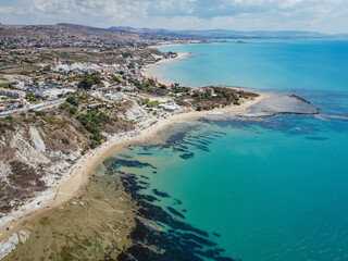 Aerial view of white rocky cliffs at Scala dei Turchi, Sicily, Italy, with turquoise clear water. Drone shot of the limestone rock formation and beach