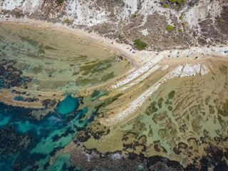 Aerial view of white rocky cliffs at Scala dei Turchi, Sicily, Italy, with turquoise clear water. Drone shot of the limestone rock formation and beach