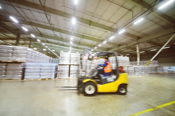 loader on the background of a huge industrial food warehouse with plastic PET bottles with beer,  water,  drinks.