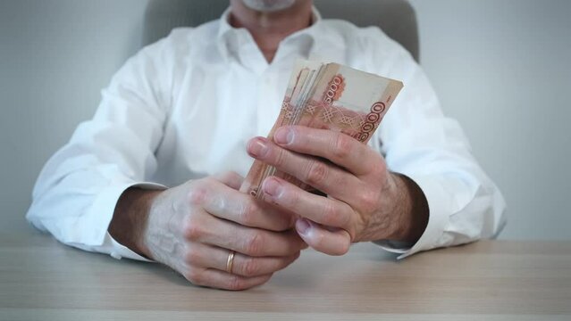 A man counts out a bundle of five thousand Russian ruble banknotes . Cash banknotes. The concept of bribery and corruption. Finance and investments. Close-up.