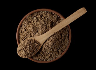 Organic linseed protein powder pile in clay pot and wooden spoon isolated on black, top view   - obrazy, fototapety, plakaty