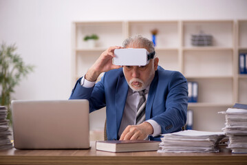 Aged male employee wearing virtual glasses in the office