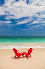 Red chairs on sandy beach by ocean Bahamas