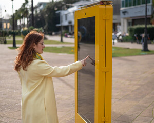 Caucasian woman using touch information board outdoors. 