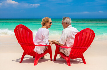 Happy retired couple enjoying togetherness by turquoise ocean