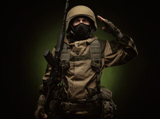 a Russian soldier in a helmet in military clothes with a Kalashnikov assault rifle on a dark...